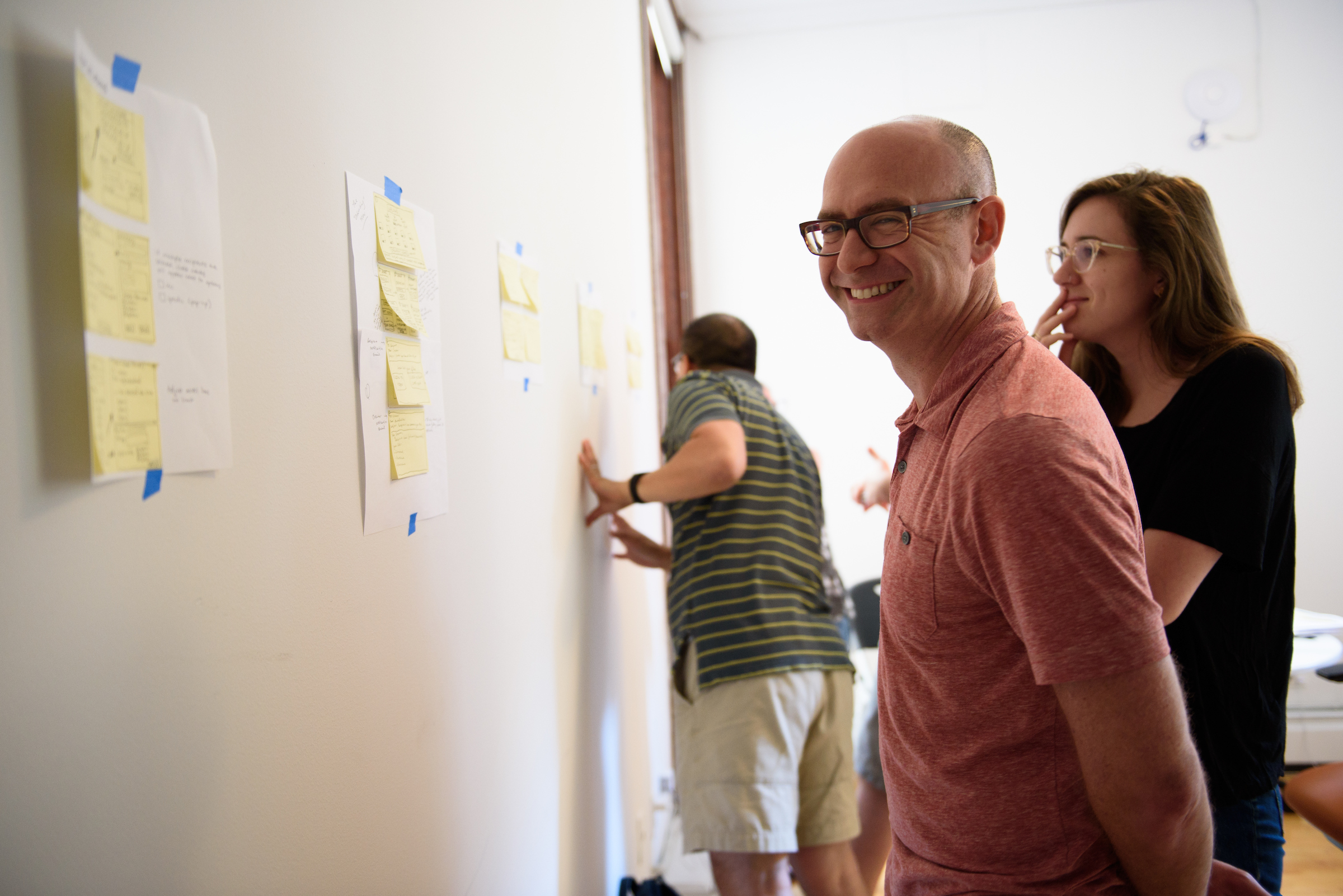 GV sprint participants stand in front of a wall with sticky notes, smiling.